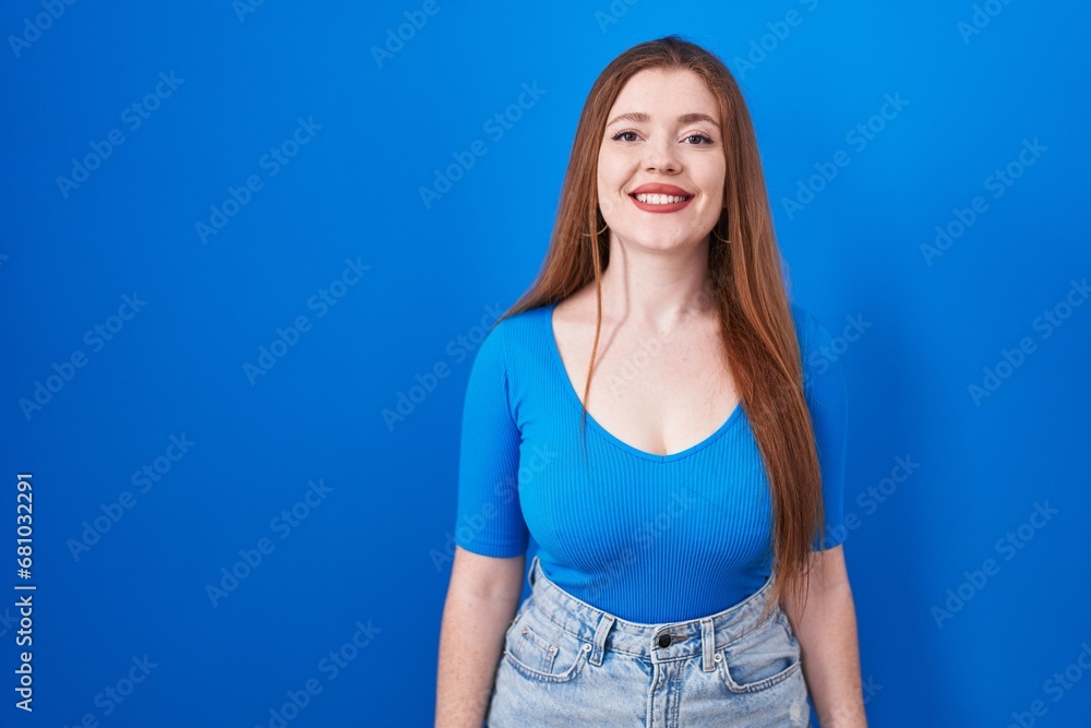 Redhead woman standing over blue background with a happy and cool smile on face. lucky person. Redhead woman standing over blue background with a happy and cool smile on face. lucky person.