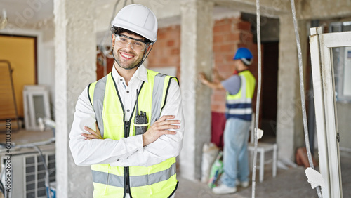 Two men builders standing with arms crossed gesture working at construction site