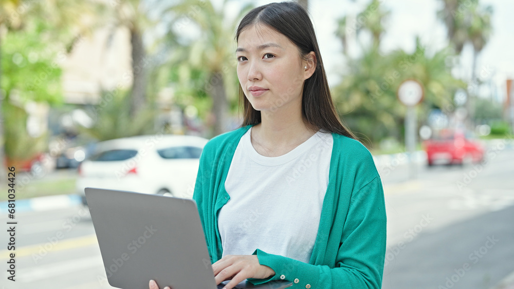 Young chinese woman using laptop with serious expression at street Young chinese woman using laptop with serious expression at street