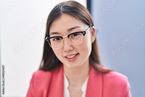 Chinese woman business worker smiling confident sitting on table at office