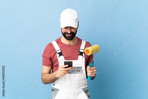 Fototapeta Naklejka Na Ścianę i Meble -  Adult painter man over isolated blue background sending a message with the mobile