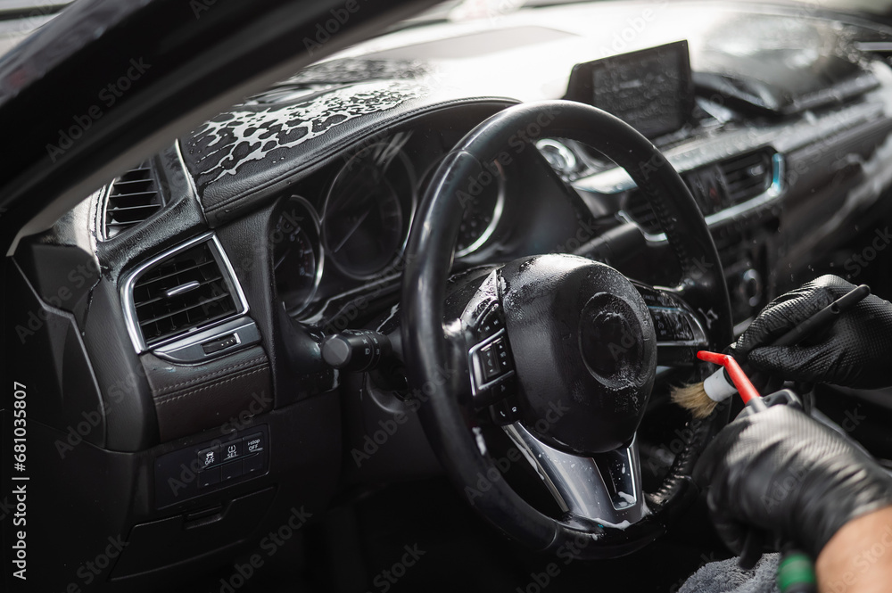 A mechanic cleans the interior of a car with a brush.