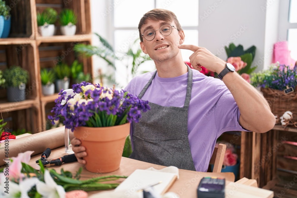 Caucasian blond man working at florist shop smiling cheerful showing and pointing with fingers teeth and mouth. dental health concept.