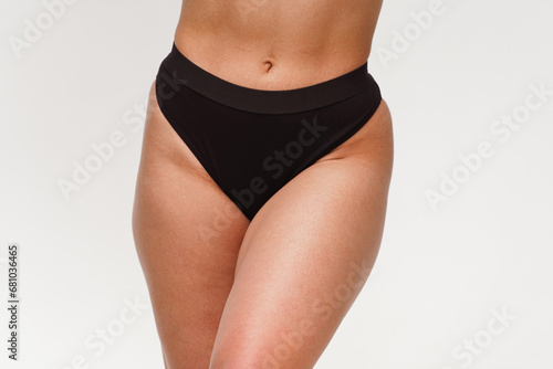 A woman with a beautiful feminine figure in black lingerie with overweight, cellulite and stretch marks.