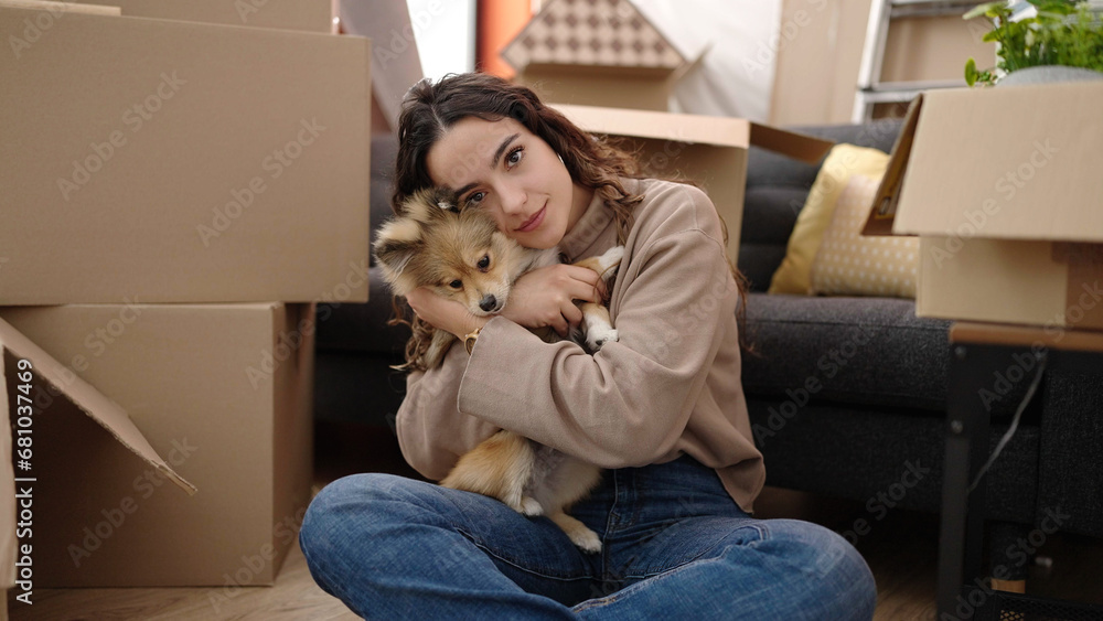 Young hispanic woman with dog sitting on floor hugging at new home Young hispanic woman with dog sitting on floor hugging at new home