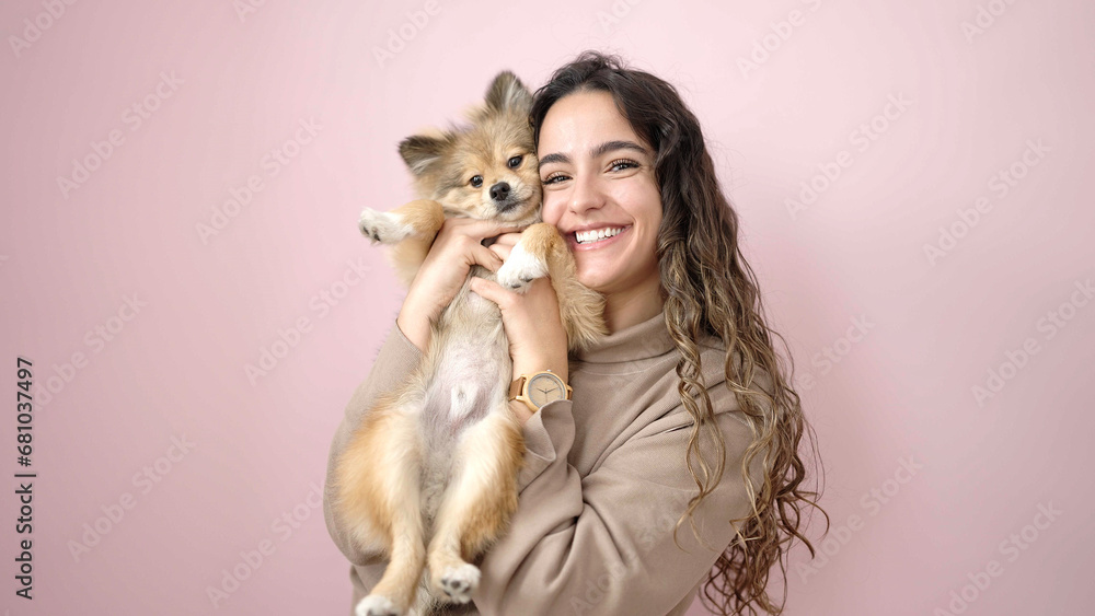 Young hispanic woman with dog smiling confident standing over isolated pink background Young hispanic woman with dog smiling confident standing over isolated pink background