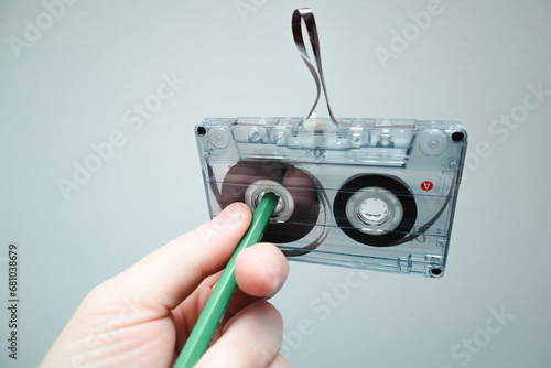 Classic cassette tape. Hand rewinding a cassette tape with a pen. 90's concepts. Vintage audio cassette tape on white background. photo