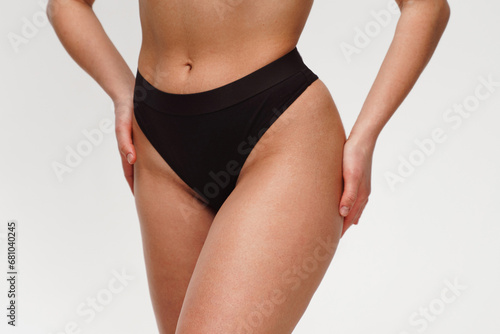 A woman with a beautiful feminine figure in black lingerie with overweight, cellulite and stretch marks.
