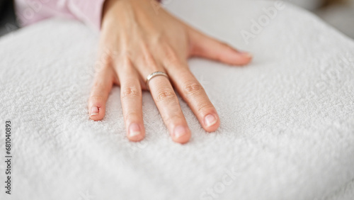 Young beautiful hispanic woman touching folded towels at laundry room