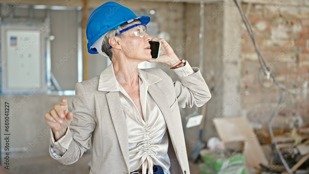 Middle age blonde woman architect talking on smartphone at construction site Middle age blonde woman architect talking on smartphone at construction site