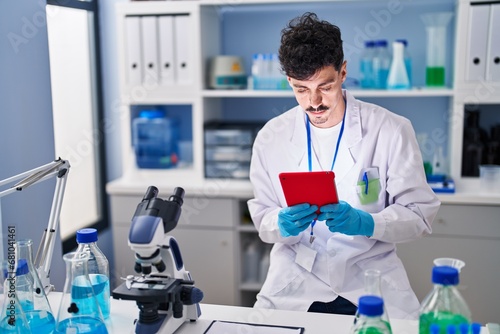 Young caucasian man scientist using touchpad at laboratory
