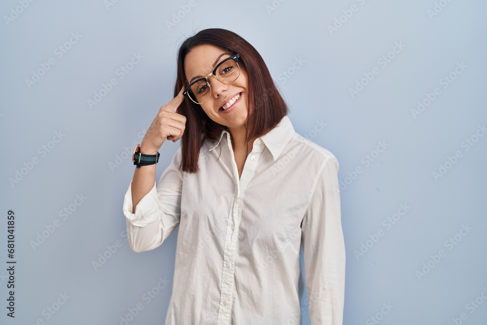 Young hispanic woman standing over white background smiling pointing to head with one finger, great idea or thought, good memory Young hispanic woman standing over white background smiling pointing to head with one finger, great idea or thought, good memory