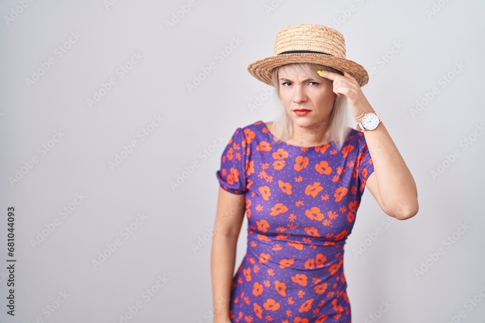 Young caucasian woman wearing flowers dress and summer hat pointing unhappy to pimple on forehead, ugly infection of blackhead. acne and skin problem Young caucasian woman wearing flowers dress and summer hat pointing unhappy to pimple on forehead, ugly infection of blackhead. acne and skin problem