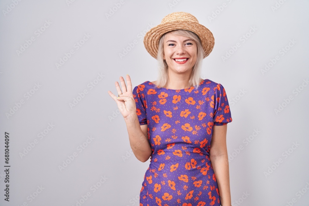Young caucasian woman wearing flowers dress and summer hat showing and pointing up with fingers number four while smiling confident and happy. Young caucasian woman wearing flowers dress and summer hat showing and pointing up with fingers number four while smiling confident and happy.