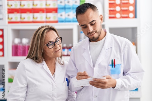 Man and woman pharmacist reading prescription at pharmacy