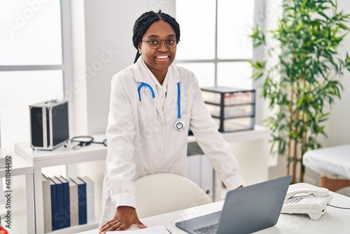 African american woman doctor smiling confident by table at clinic