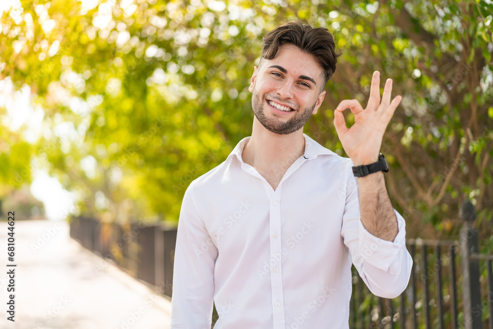 Young handsome man at outdoors showing ok sign with fingers Young handsome man at outdoors showing ok sign with fingers