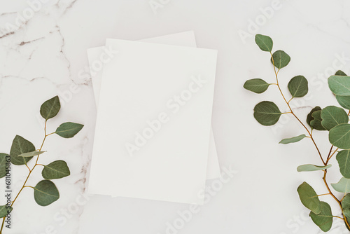 Empty blank white magazine cover mock up and green eucalyptus branch on white marble table background.