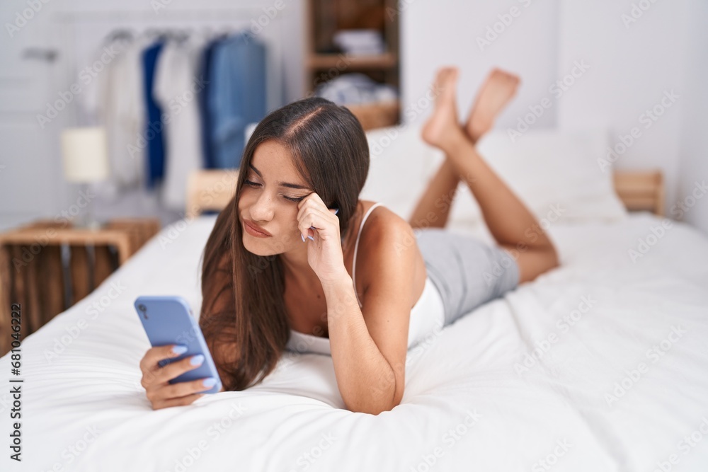 Young beautiful hispanic woman using smartphone with serious expression at bedroom Young beautiful hispanic woman using smartphone with serious expression at bedroom