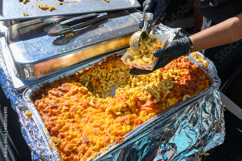 Hands Serving Jerk Chicken Mac and Cheese at the Poboy Festival on Oak Street in New Orleans, LA, USA photo