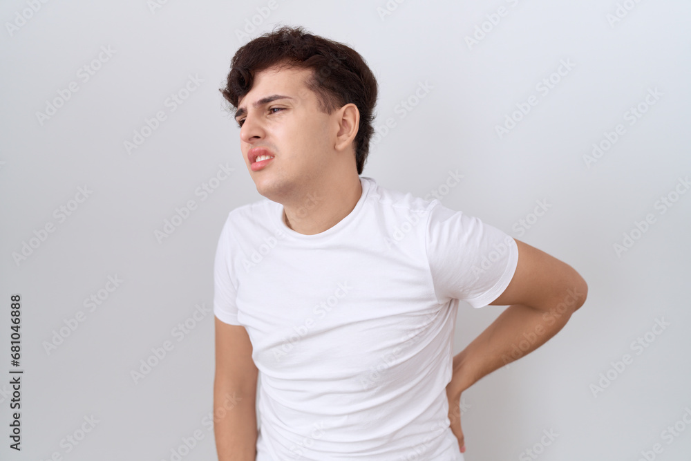 Young non binary man wearing casual white t shirt suffering of backache, touching back with hand, muscular pain