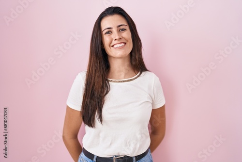 Young brunette woman standing over pink background with a happy and cool smile on face. lucky person.