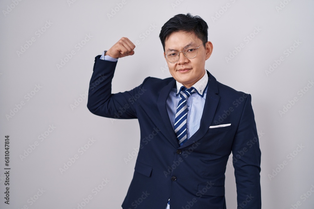Young asian man wearing business suit and tie strong person showing arm muscle, confident and proud of power Young asian man wearing business suit and tie strong person showing arm muscle, confident and proud of power
