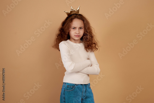 Fotografie Little offended African-american girl with long curly hair on beige background