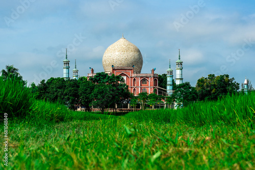 Islamic muslim Mosque against backdrop of blue sky and rice field. Bokhshia Khanka Sharif Mosque Bangladesh Ishurdi photo