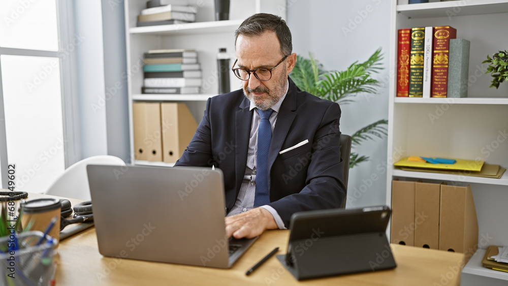 Grey-haired middle age man, business pro, working overtime at office, concentrated yet relaxed, beard & elegant suit amidst indoor tech Grey-haired middle age man, business pro, working overtime at office, concentrated yet relaxed, beard & elegant suit amidst indoor tech