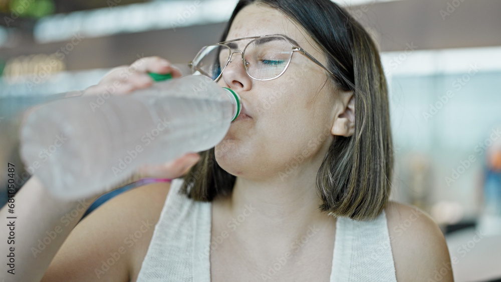 Young beautiful hispanic woman drinking bottle of water at the airport Young beautiful hispanic woman drinking bottle of water at the airport
