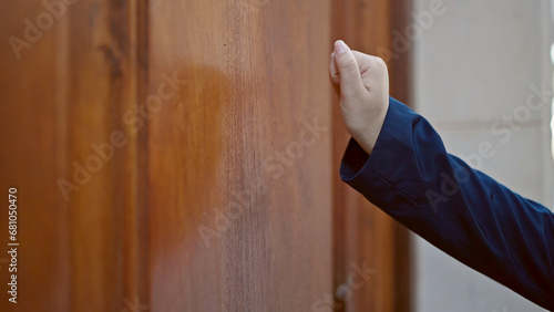 Photos Young hispanic woman knocking at the door at street