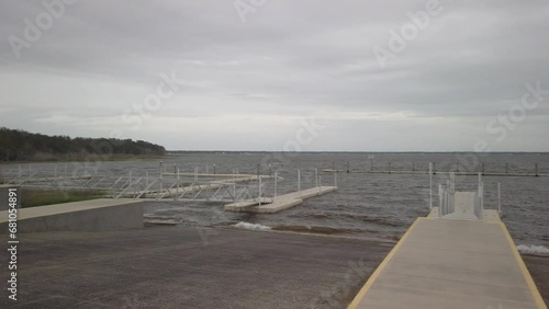 Pan left to right of Lake Weir Florida boat ramps looking east over waves in water on a cloudy overcast day.