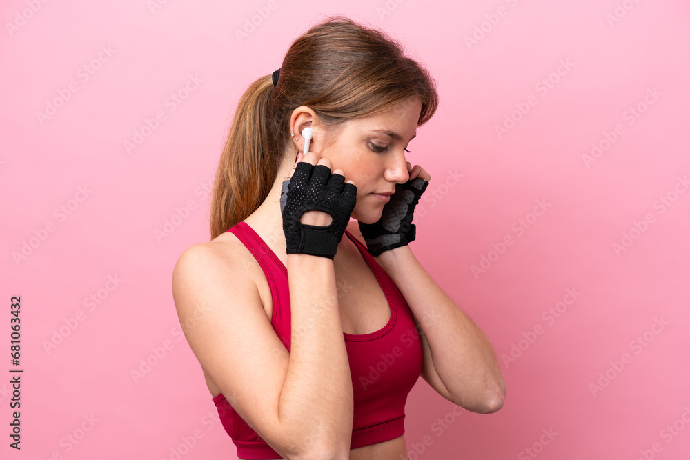 Young caucasian woman isolated on pink background listening music