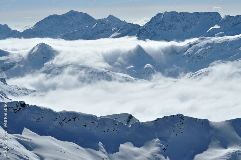 Snow covered high mountains, fog and clouds raising from above