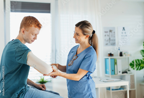 Konstfotografi Doctor checking the orthopedic cast, brace on a teenage patient's broken arm