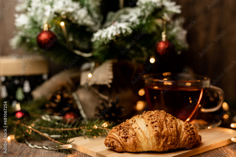 Cup of tea with croissant near Christmas tree.New Year's Eve at home with family
