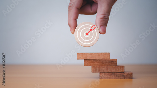 Businessman's hands hold a circular wooden board with a dartboard. It represents the concept of business strategy and target action plan. photo