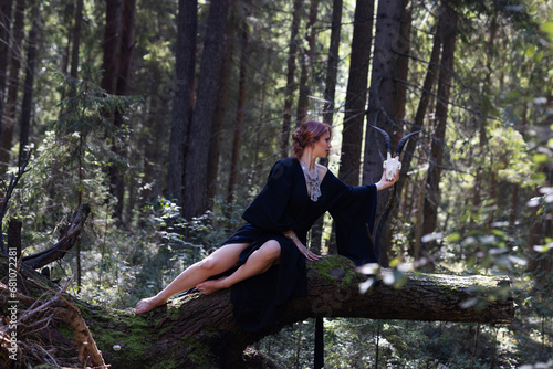 Beautiful red-haired girl. The Witch of the Woods. Sitting on a tree