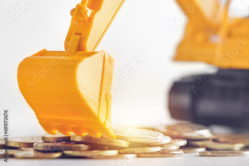 one yellow excavator collects coins in close-up. concepts of business and bank financing.