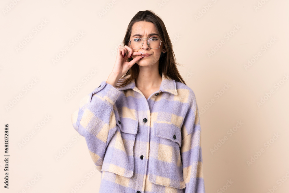 Young woman over isolated beige background showing a sign of silence gesture Young woman over isolated beige background showing a sign of silence gesture