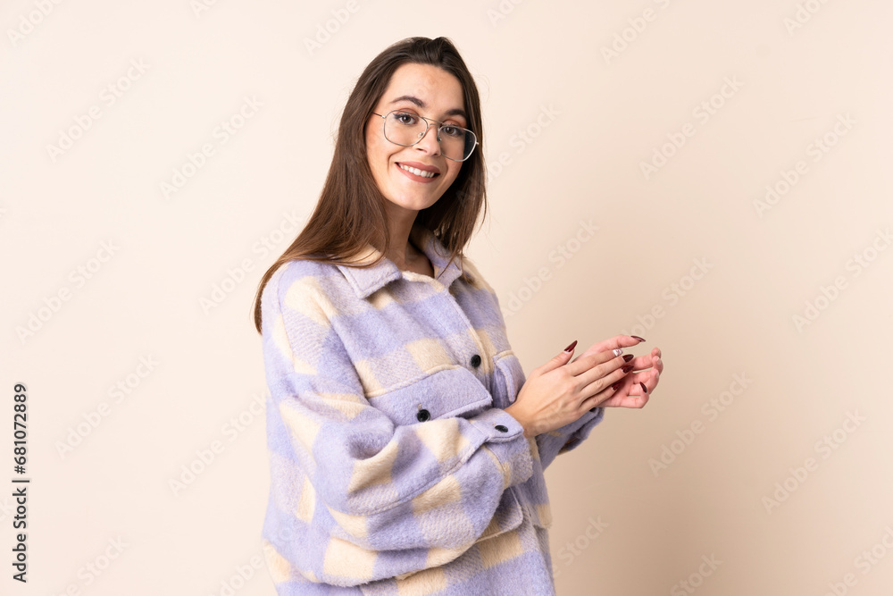 Young woman over isolated beige background applauding Young woman over isolated beige background applauding