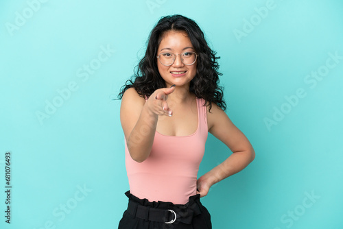 Young asian woman isolated on blue background shaking hands for closing a good deal © luismolinero