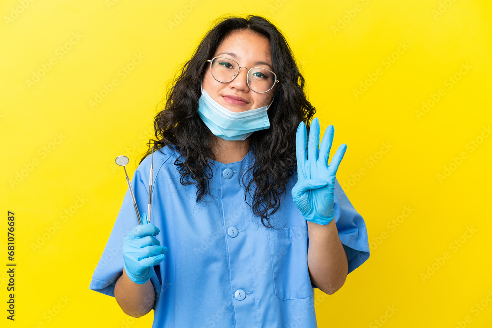 Young asian dentist holding tools over isolated background happy and counting four with fingers Young asian dentist holding tools over isolated background happy and counting four with fingers