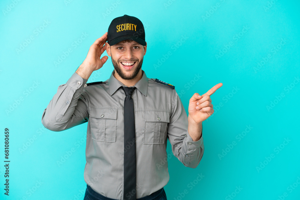 Young security man isolated on blue background surprised and pointing finger to the side Young security man isolated on blue background surprised and pointing finger to the side