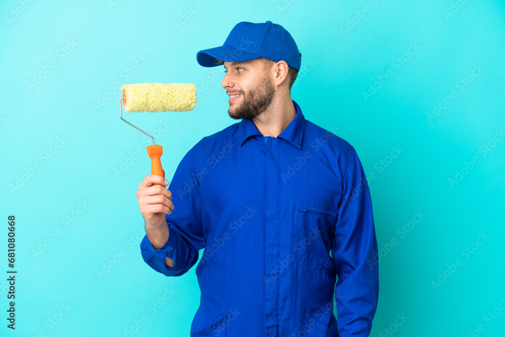 Painter caucasian man isolated on blue background looking side