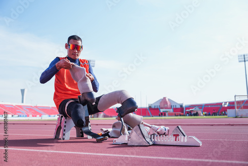 Side view of Disabled asian athlete thailand with prosthetic blades in sports center, attractive amputee sportsman runner sitting on chair at the stadium, physical limitations. © AU USAnakul+