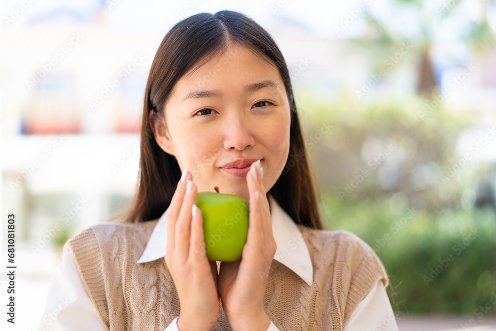 Pretty Chinese woman at outdoors holding an apple Pretty Chinese woman at outdoors holding an apple