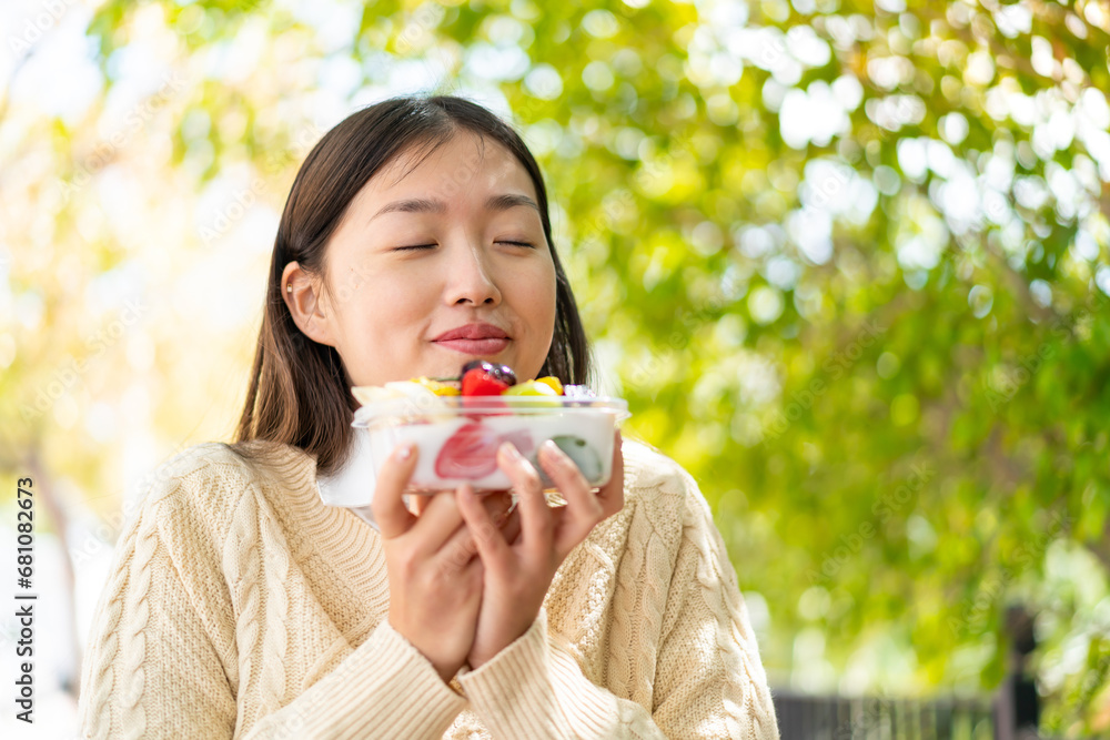 Youing chinese woman holding a bowl of fruit at outdoors Youing chinese woman holding a bowl of fruit at outdoors