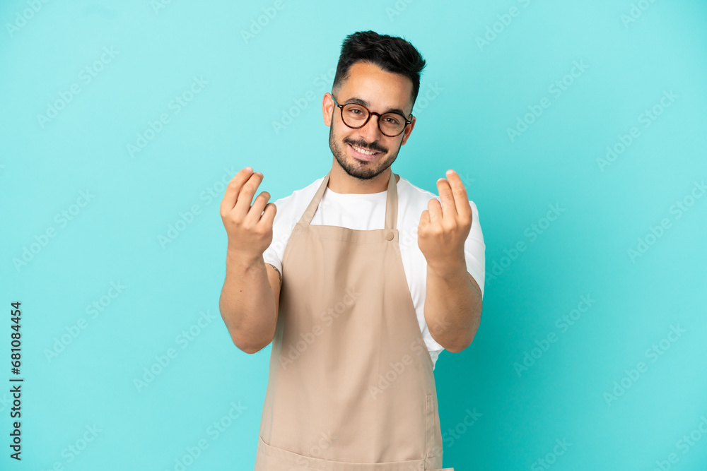 Fototapeta premium Restaurant waiter caucasian man isolated on blue background making money gesture